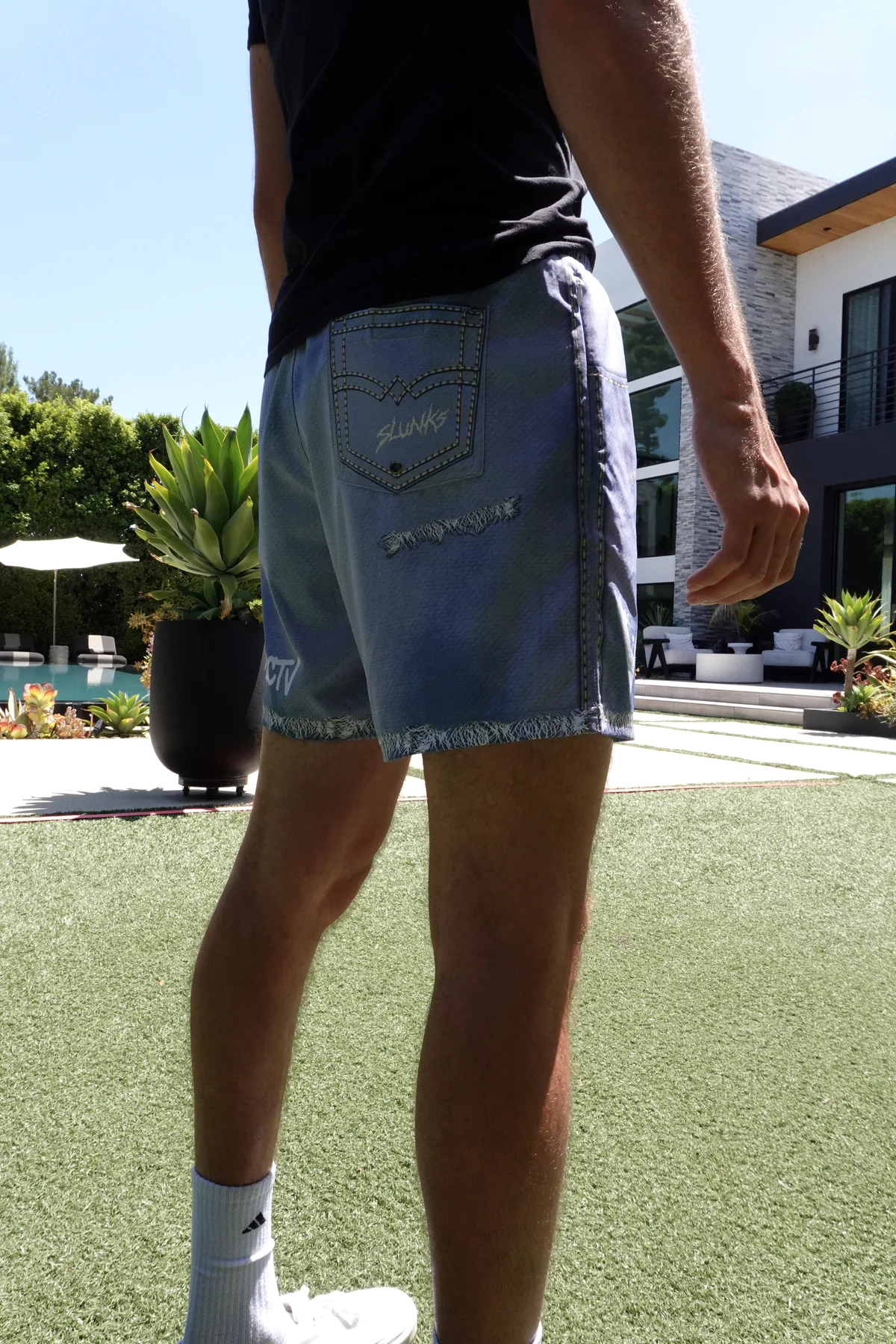 Rear on-body fit of JORTS shorts in a backyard volleyball setting