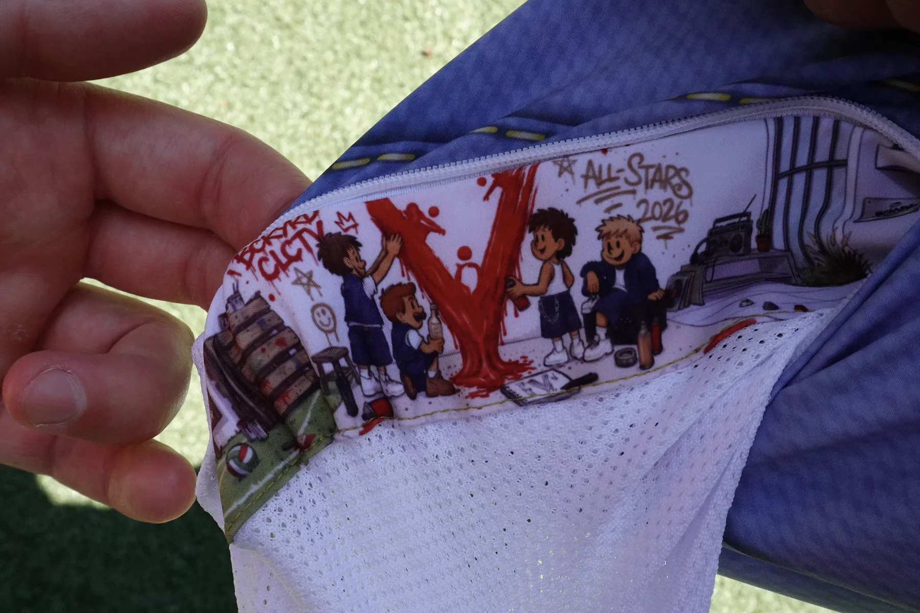 Hidden pocket lining showing the Backyard All-Stars spray painting the Volleyball Guys V