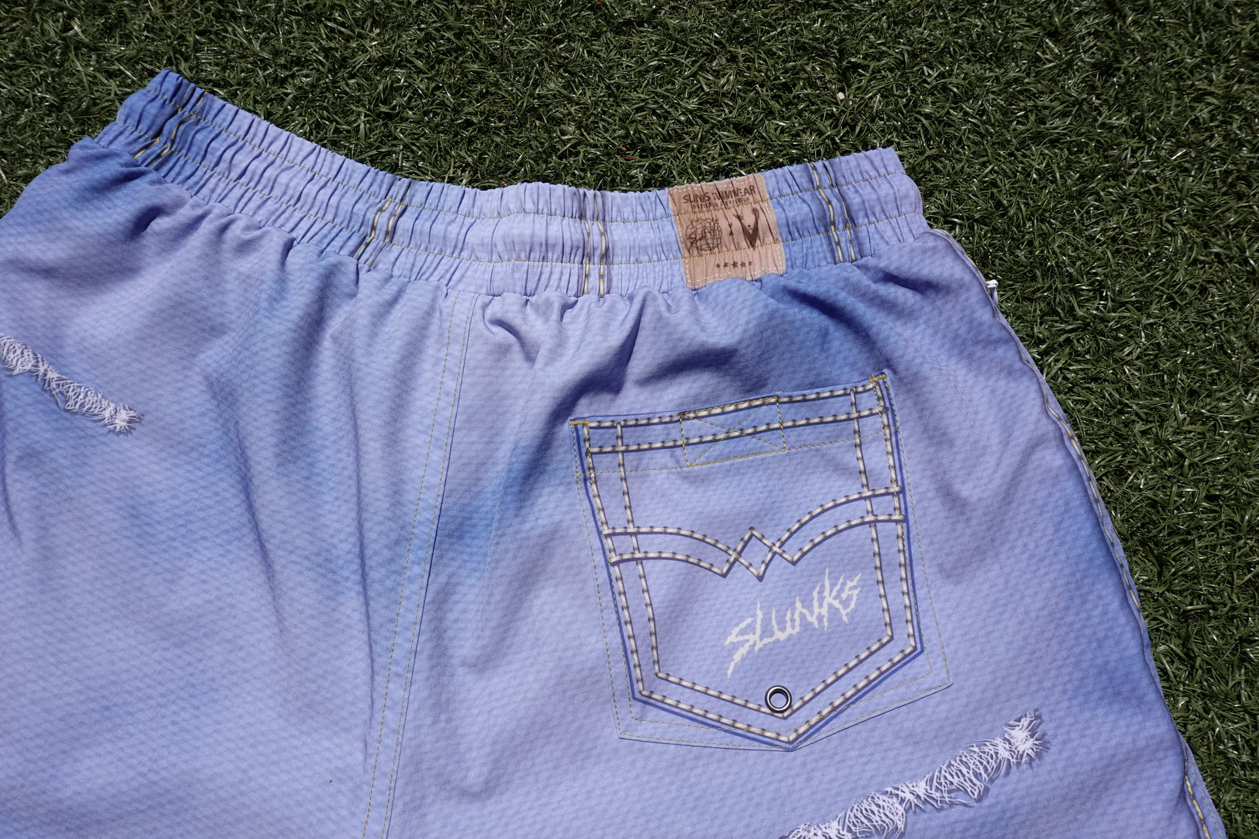 Close view of the JORTS back pocket, waistband label, gold stitching, eyelet, and distressed fabric